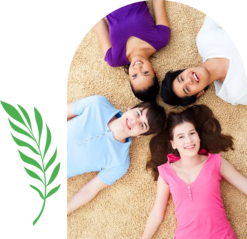 Four children lying in a circle on carpet, smiling upwards.
